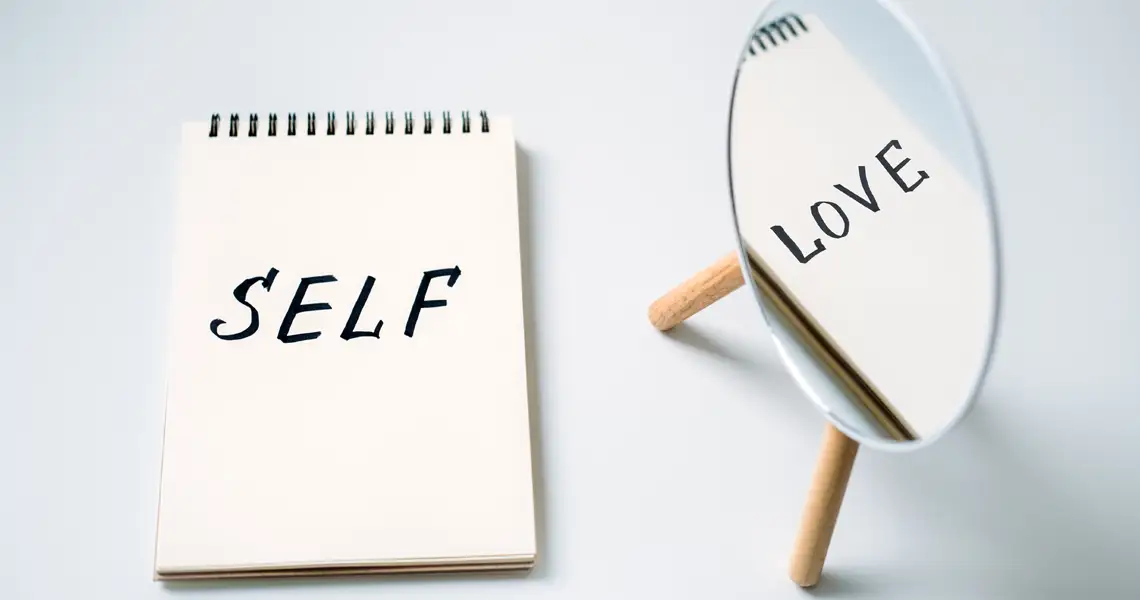cuaderno y espejo con las palabras self love