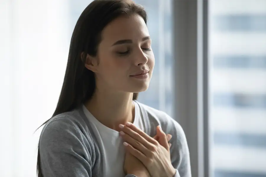 mujer con manos en el pecho respirando tranquila