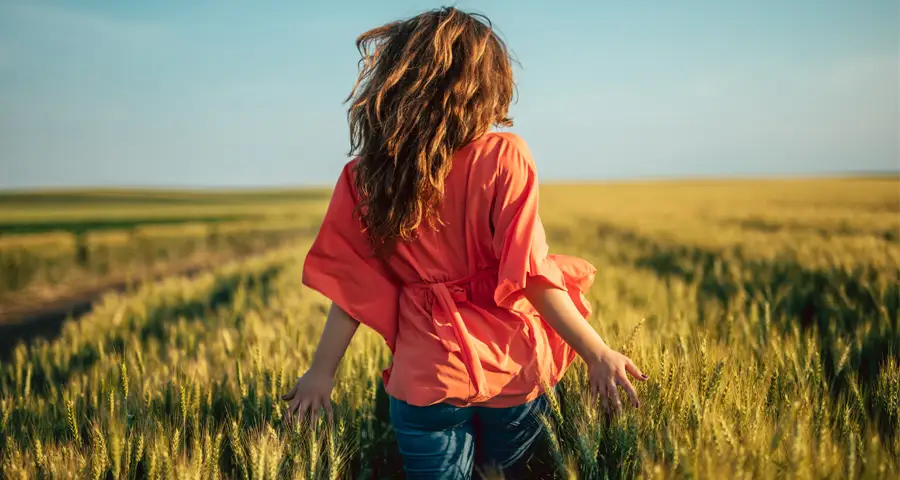 mujer caminando tranquila en un campo