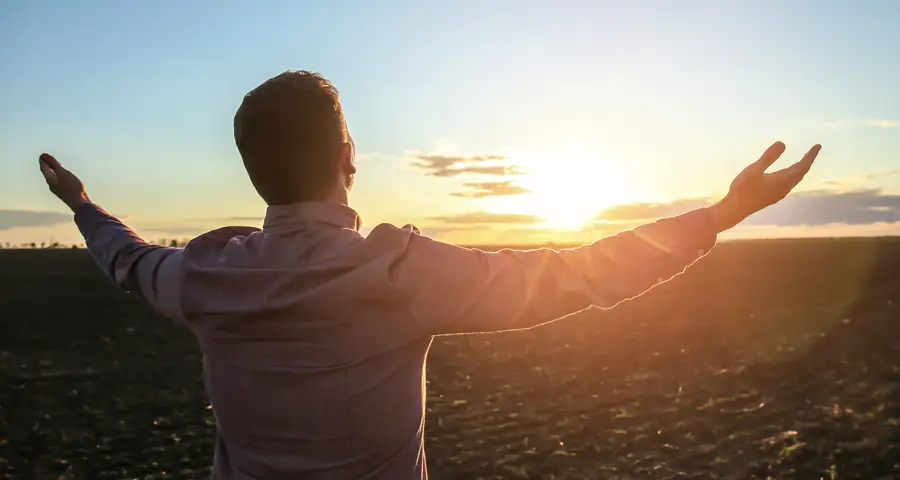 hombre esperanzado con los brazos abiertos al sol