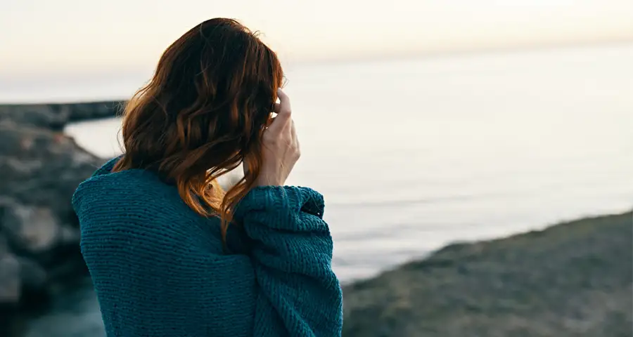mujer frente al mar con tono melancólico